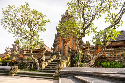 Stunning Balinese temple entrance adorned with intricate carvings and lush greenery on a sunny day.