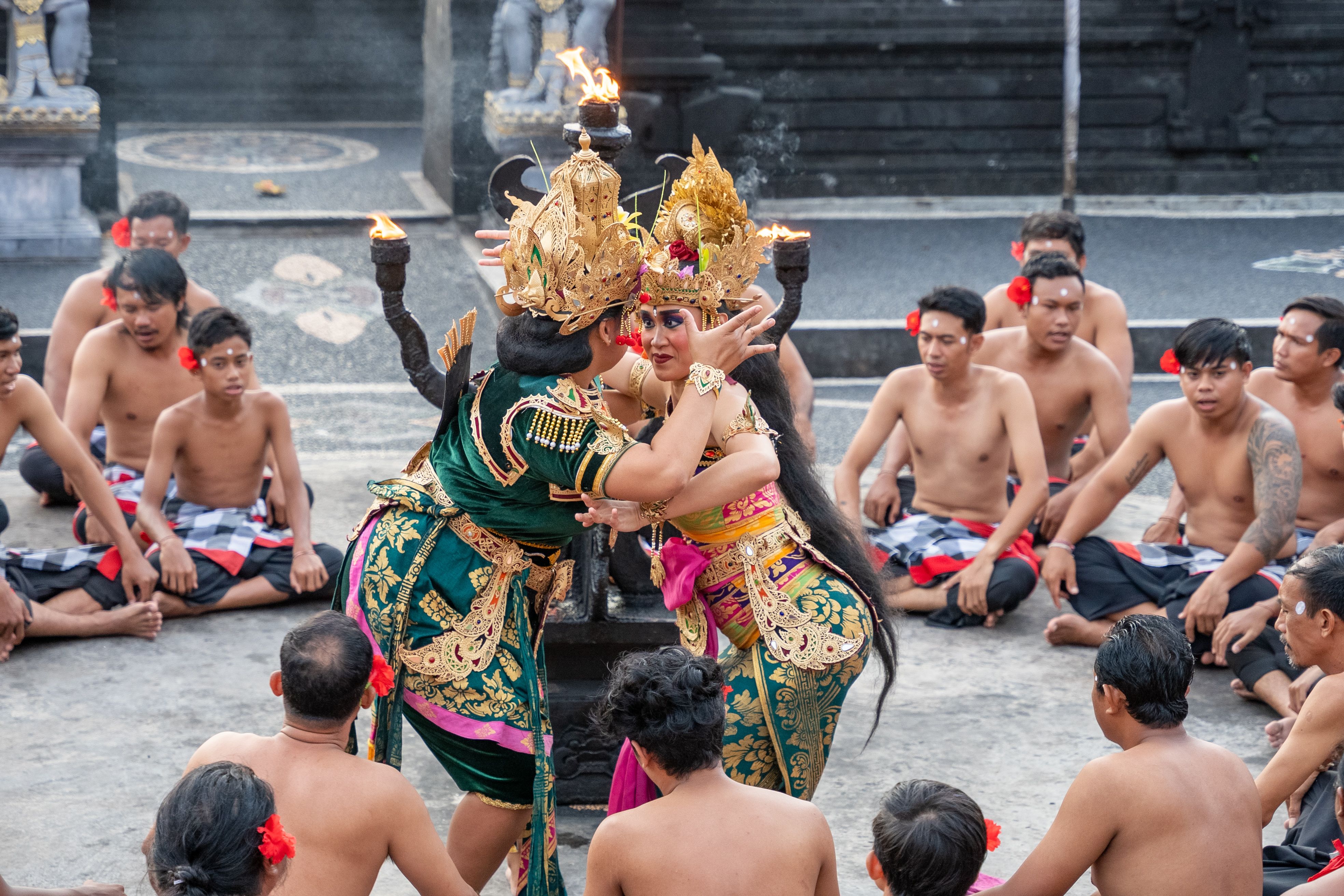 Traditional Balinese dance performance with detailed costumes and attentive audience at an outdoor ceremony.
