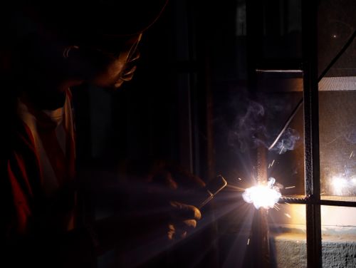 Free Silhouette of a welder sparking at night, showcasing industrial craftsmanship. Stock Photo