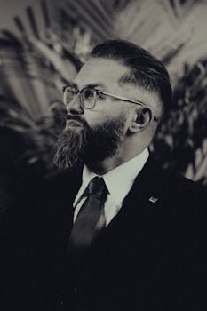 Stylish bearded man in vintage suit and glasses in sepia tone. Elegant and sophisticated.