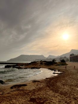 A tranquil view of Calpe beach during sunset, showcasing the Mediterranean coast of Spain.