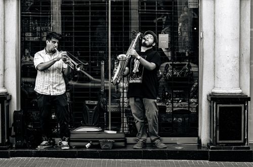 Free Two street musicians playing trumpet and saxophone in Buenos Aires, creating a lively urban scene. Stock Photo