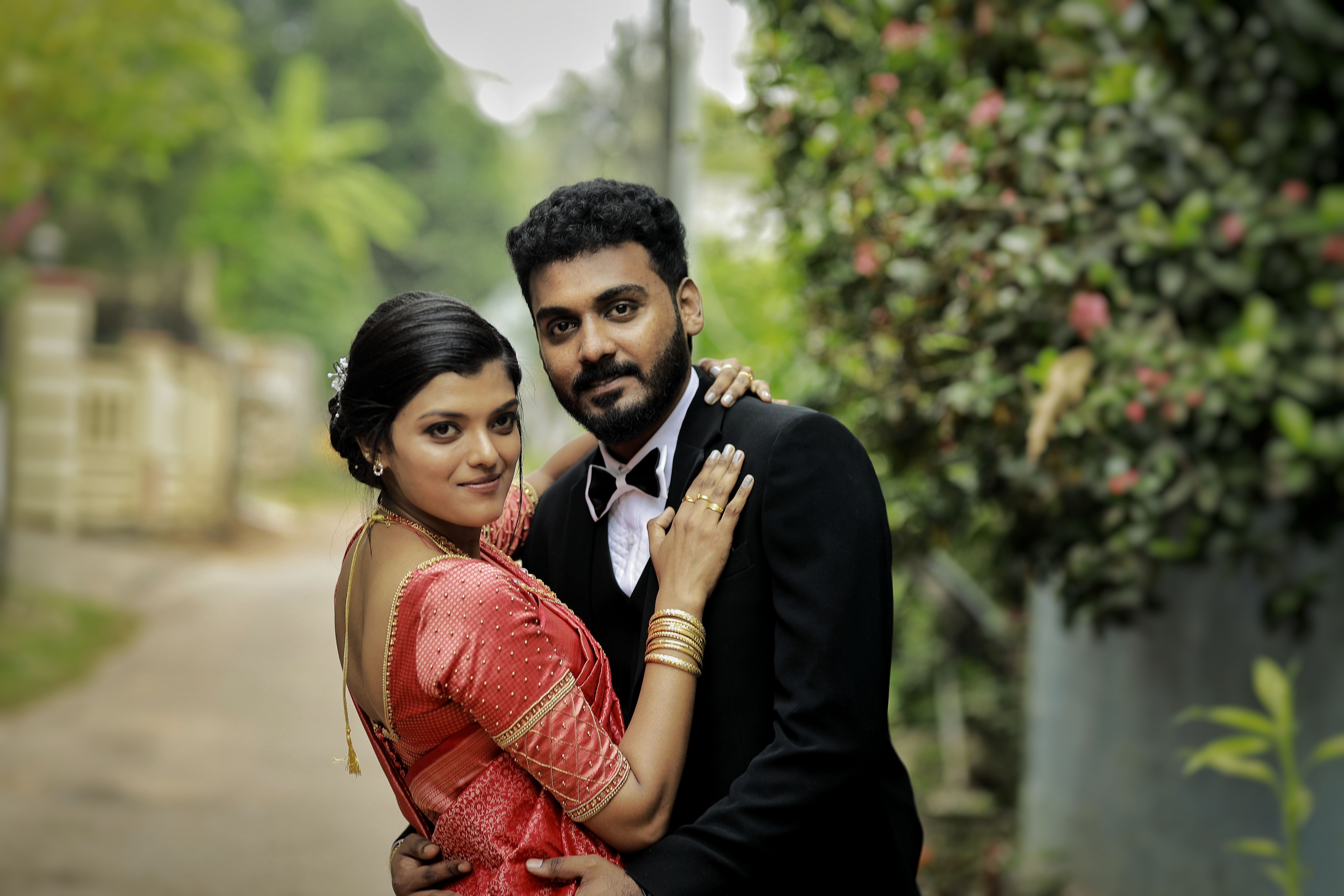 A beautiful South Asian couple poses elegantly in traditional attire outdoors, capturing a romantic wedding moment.
