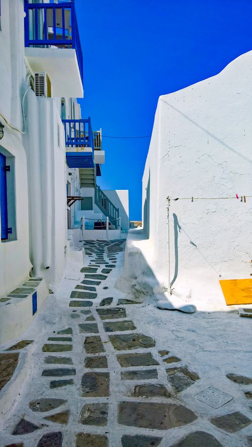 Free Explore a classic Greek island street with whitewashed walls and blue accents in Mykonos. Stock Photo