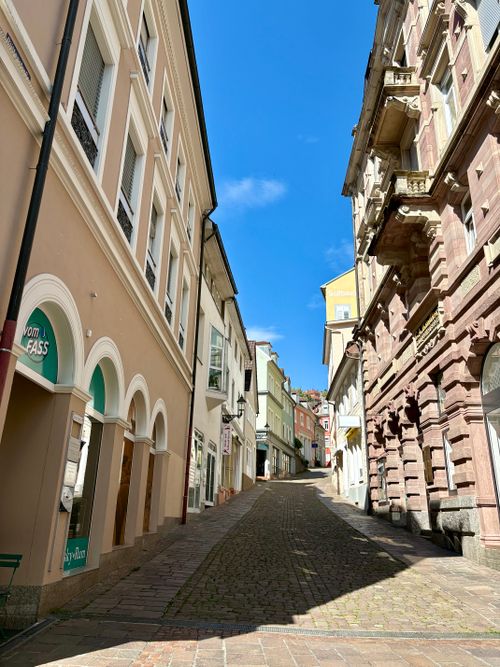 Free Charming European village street with cobblestone path and colorful historic buildings under a clear blue sky. Stock Photo