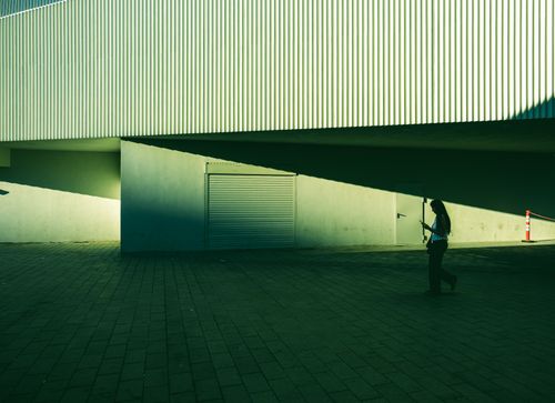 Free A solitary figure walks amidst striking architectural shadows in Istanbul's Kabataş district. Stock Photo