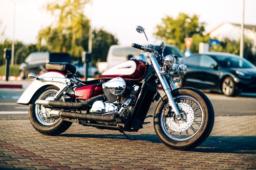Free A vintage motorcycle parked on a cobblestone street during sunset, showcasing urban vibes. Stock Photo