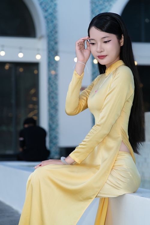 Free Elegant woman in a yellow traditional dress posing indoors with soft lighting. Stock Photo