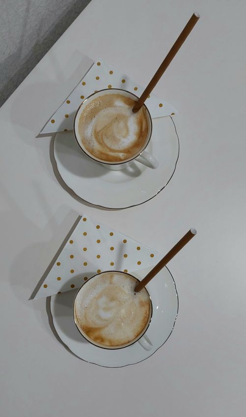 Free Two cappuccino cups with straws on a white table, featuring polka dot napkins. Stock Photo