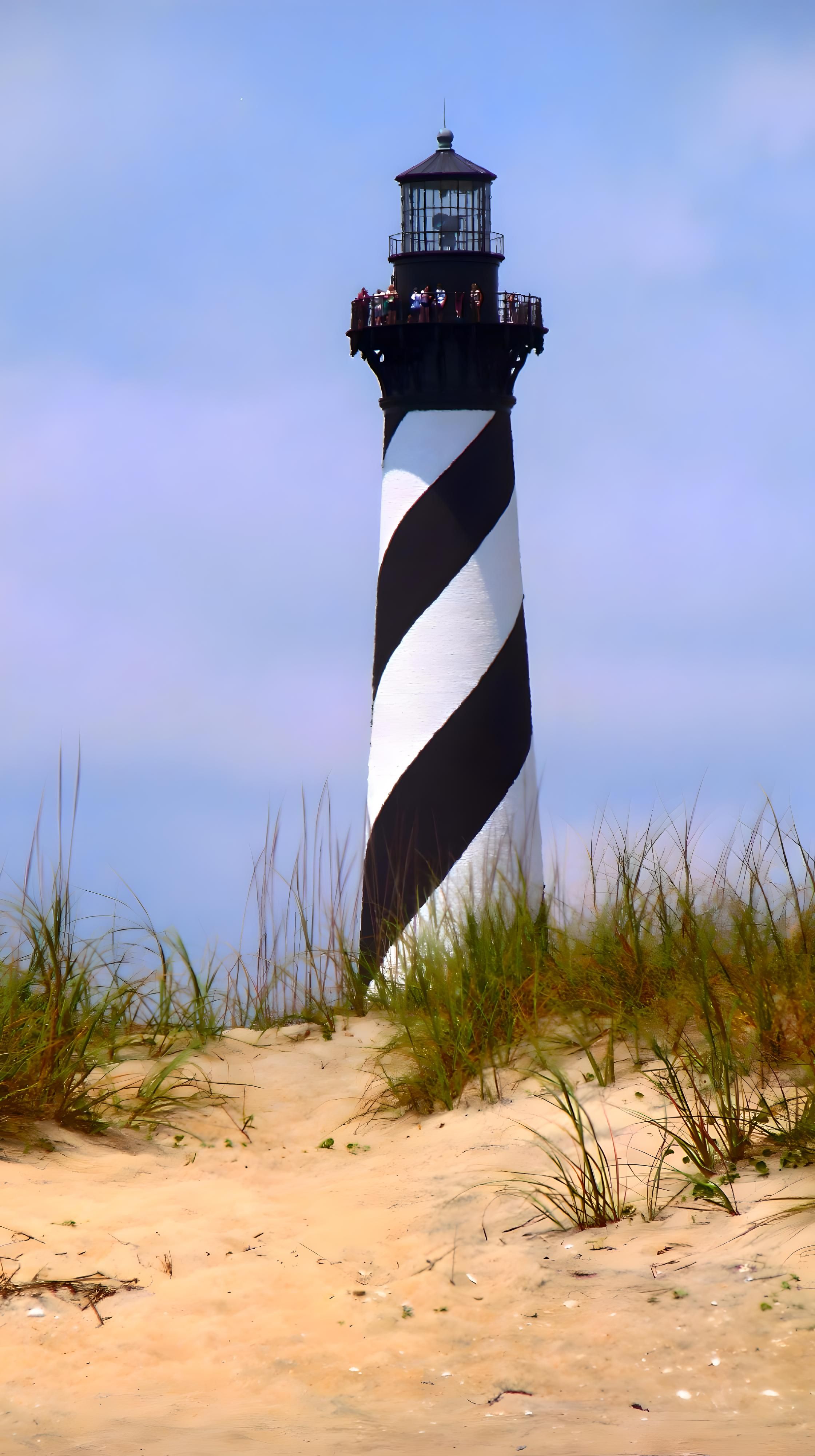 View of Cape Hatteras Lighthouse with sandy dune foreground in North Carolina.