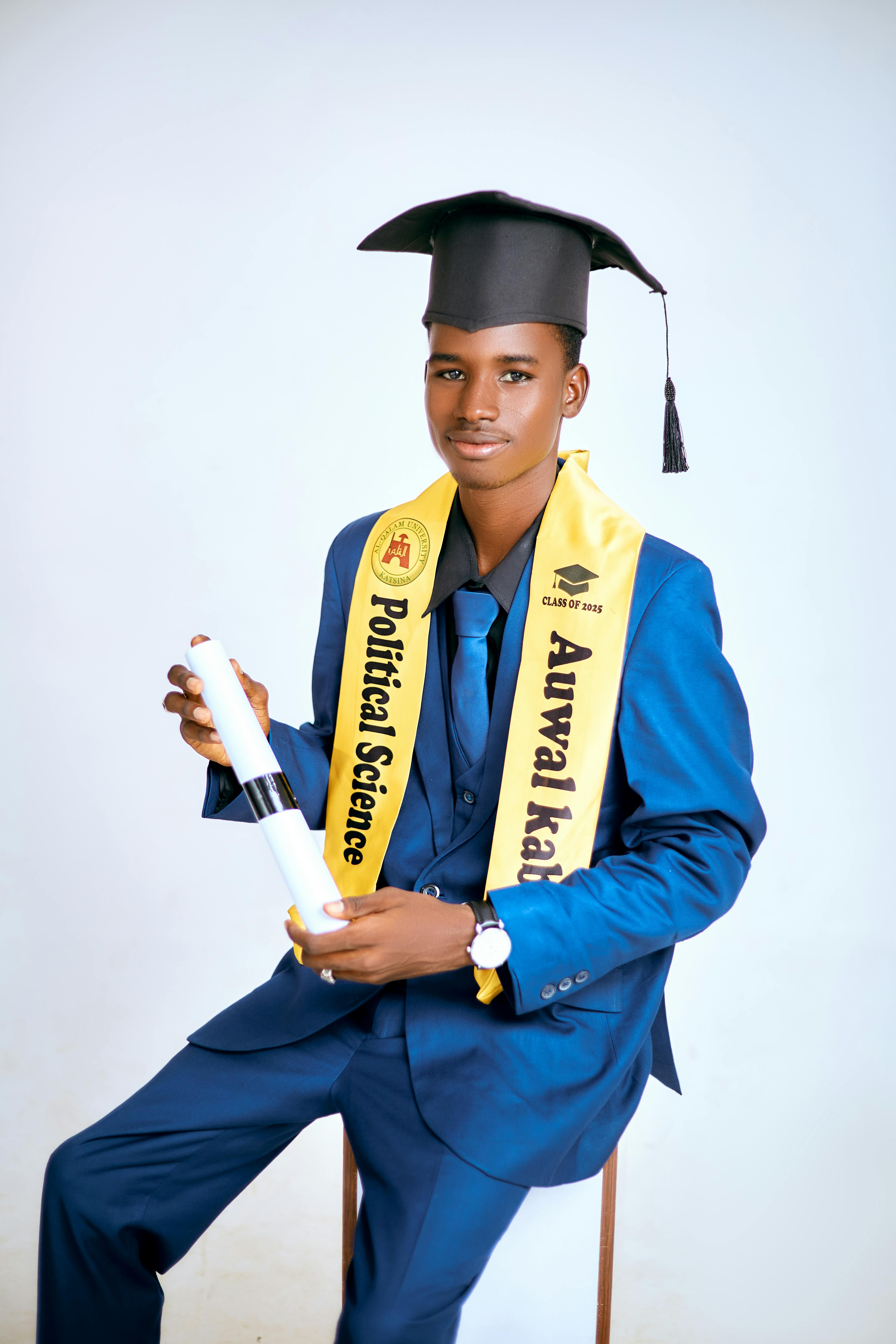 Young man in graduation attire holding diploma, symbolizing achievement in political science.