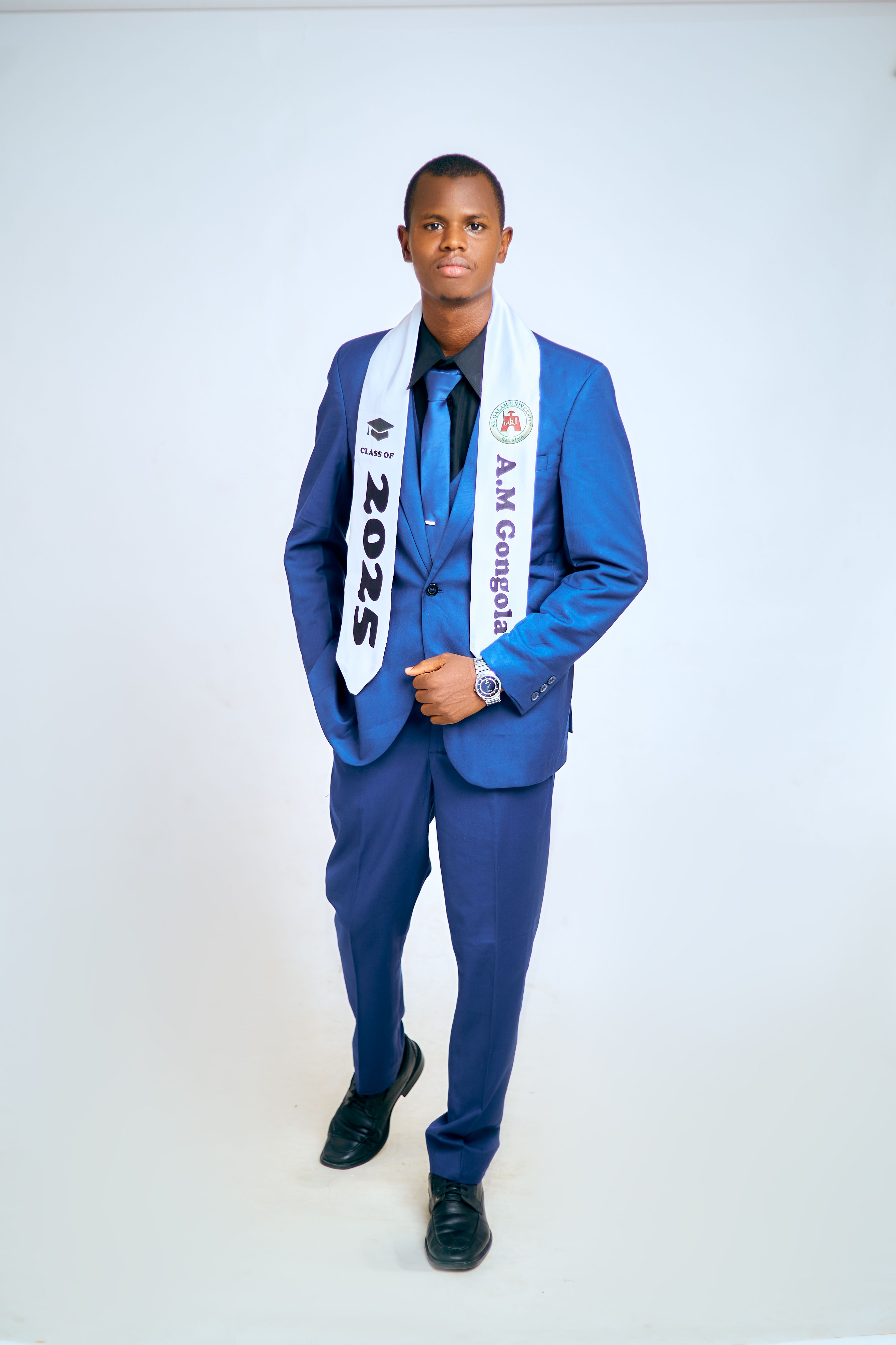 Portrait of a young man in a blue suit wearing a 2025 graduation sash, standing confidently.
