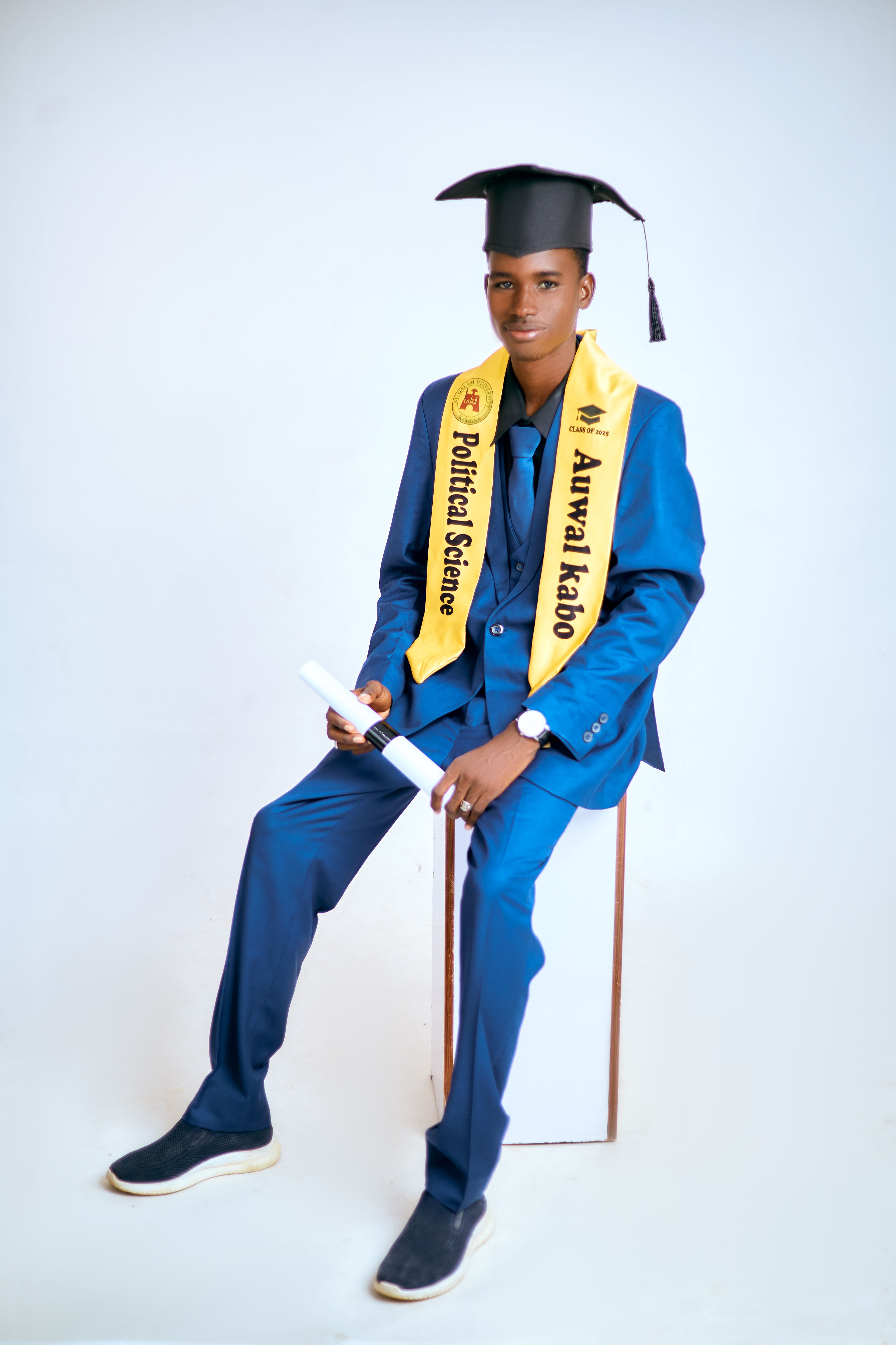Young adult in graduation cap and gown with a diploma, celebrating academic achievement.
