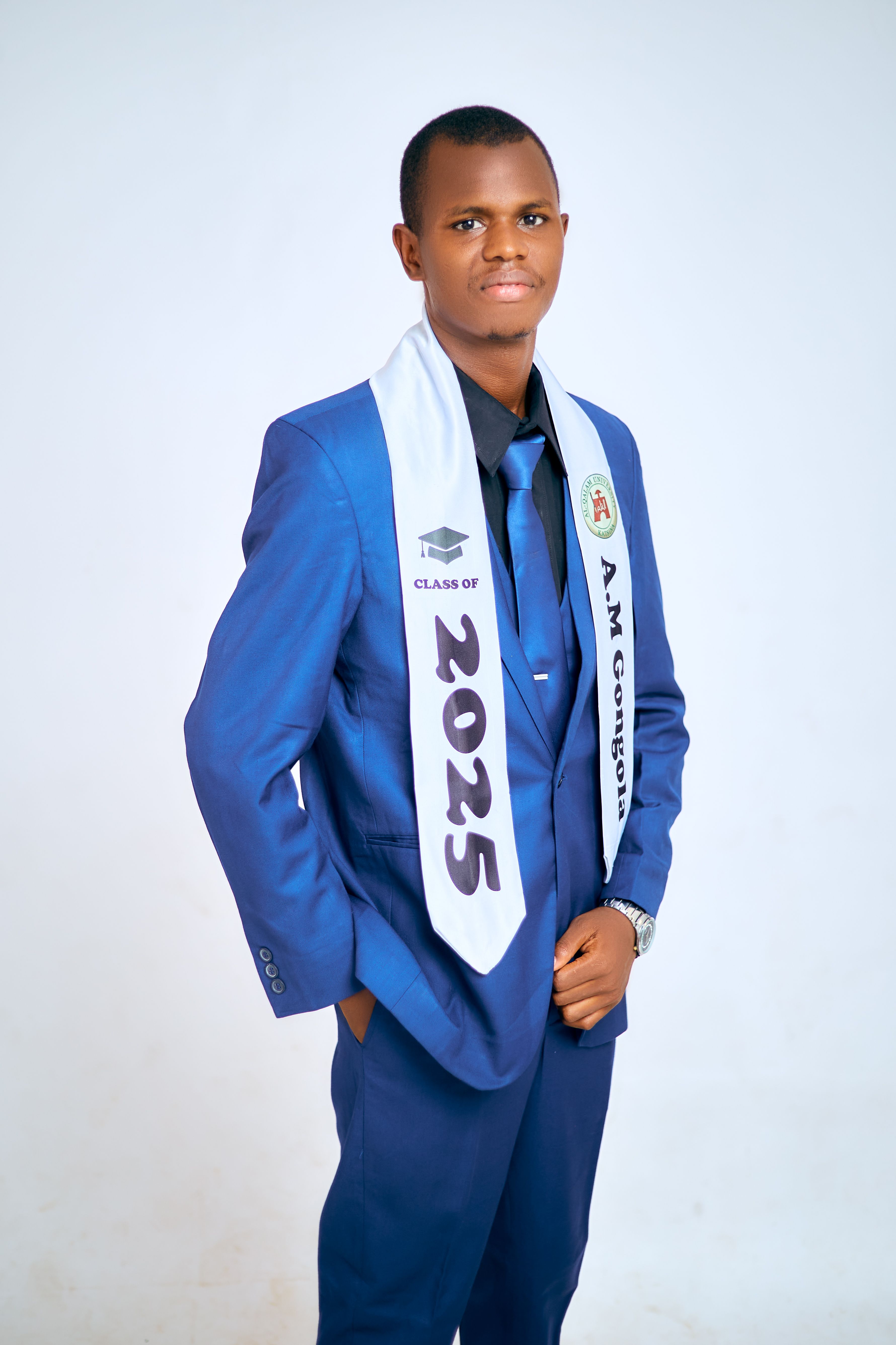 Confident young man in blue suit wearing a graduation sash marked Class of 2025.