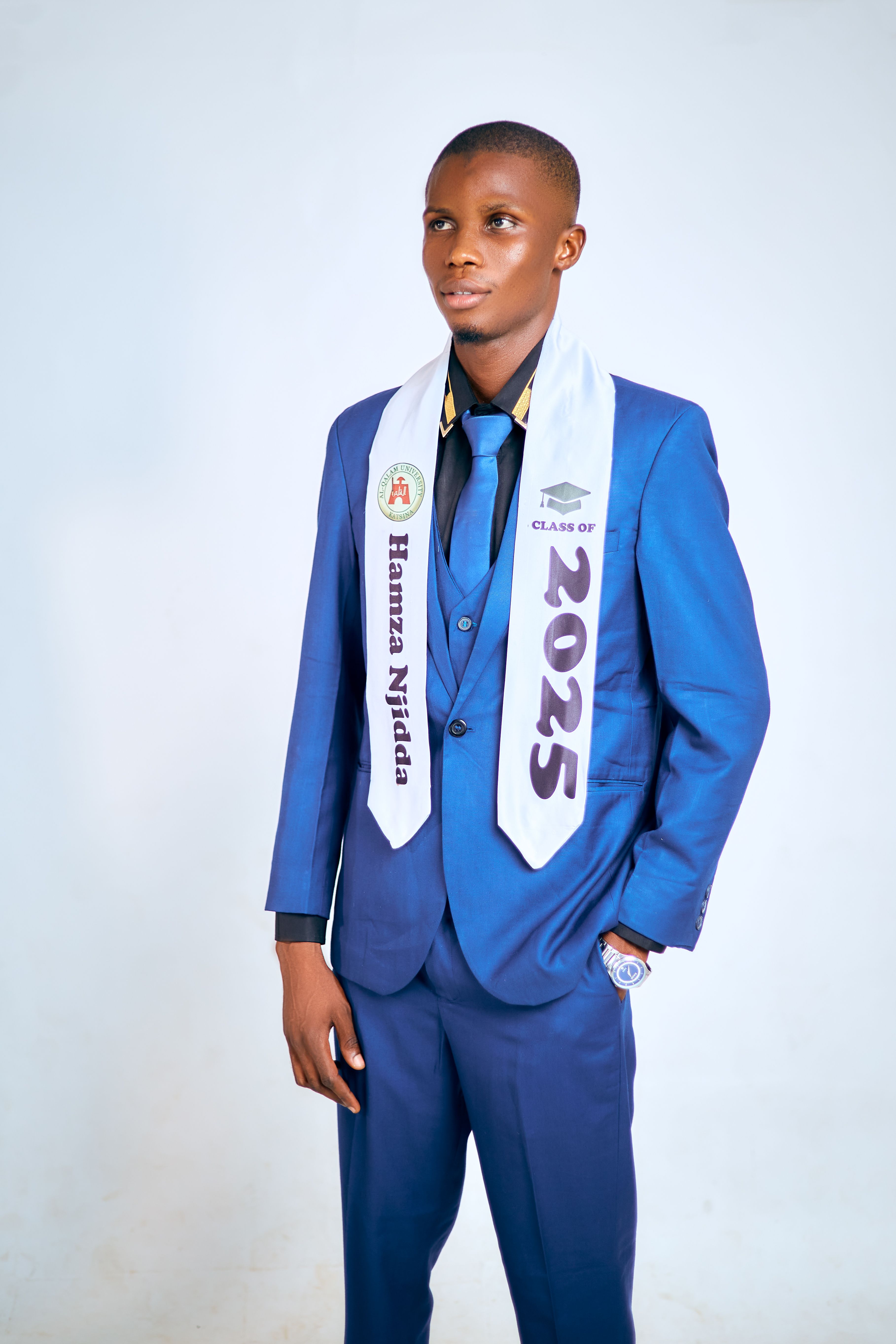 Young adult male wearing a blue suit and graduation sash marked 2025.