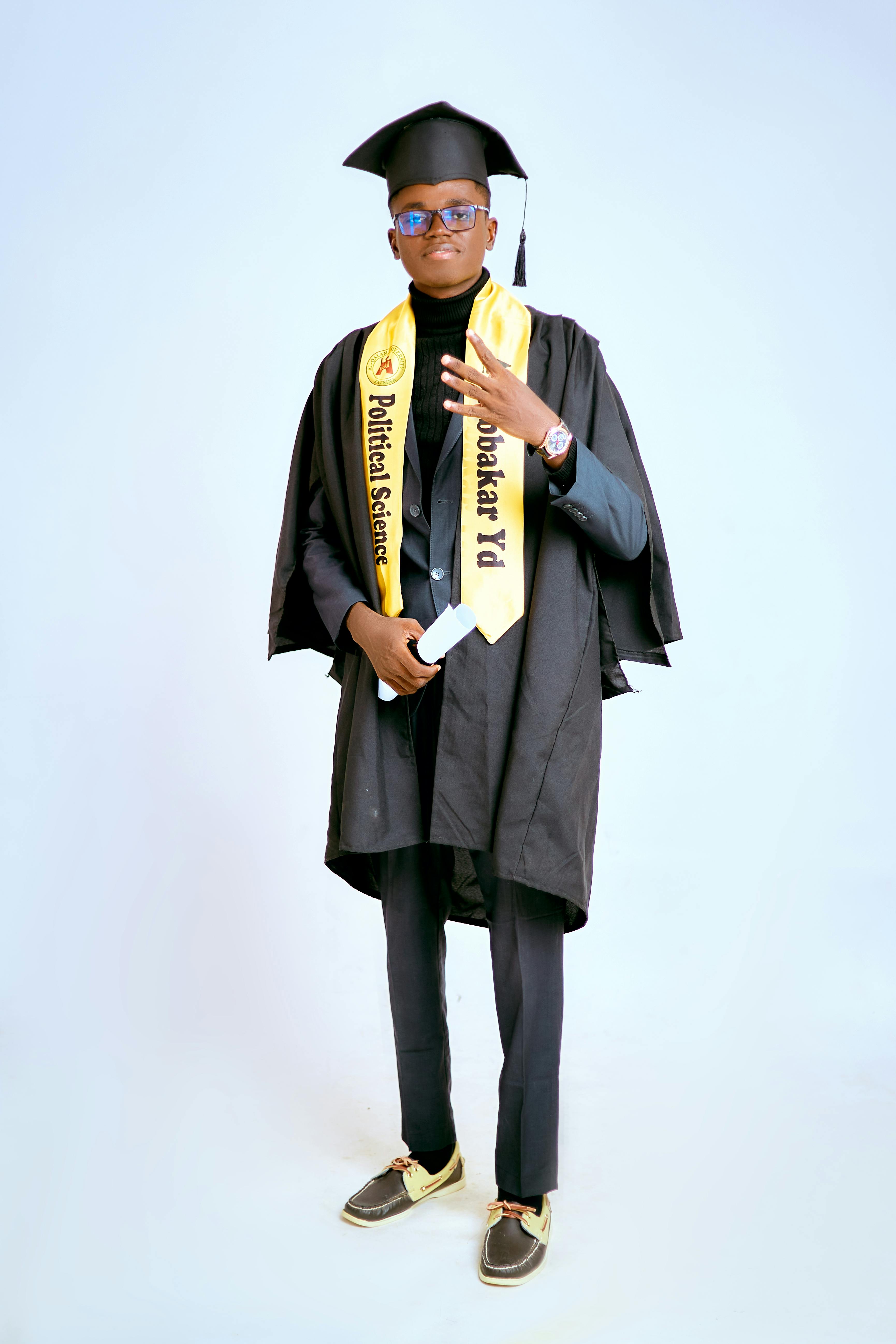 Portrait of a young adult male in graduation gown, celebrating academic achievement.