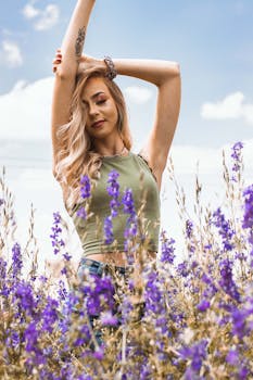 一位时尚的女士在盛开的紫色花田里，于清澈的蓝天下摆出姿势，散发着优雅与欢乐