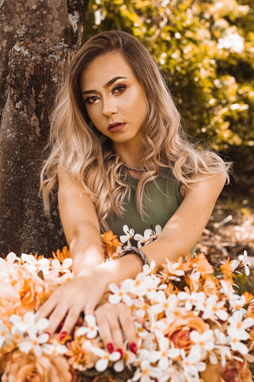 Woman in Green Tank Top Lying on Brown Leaves