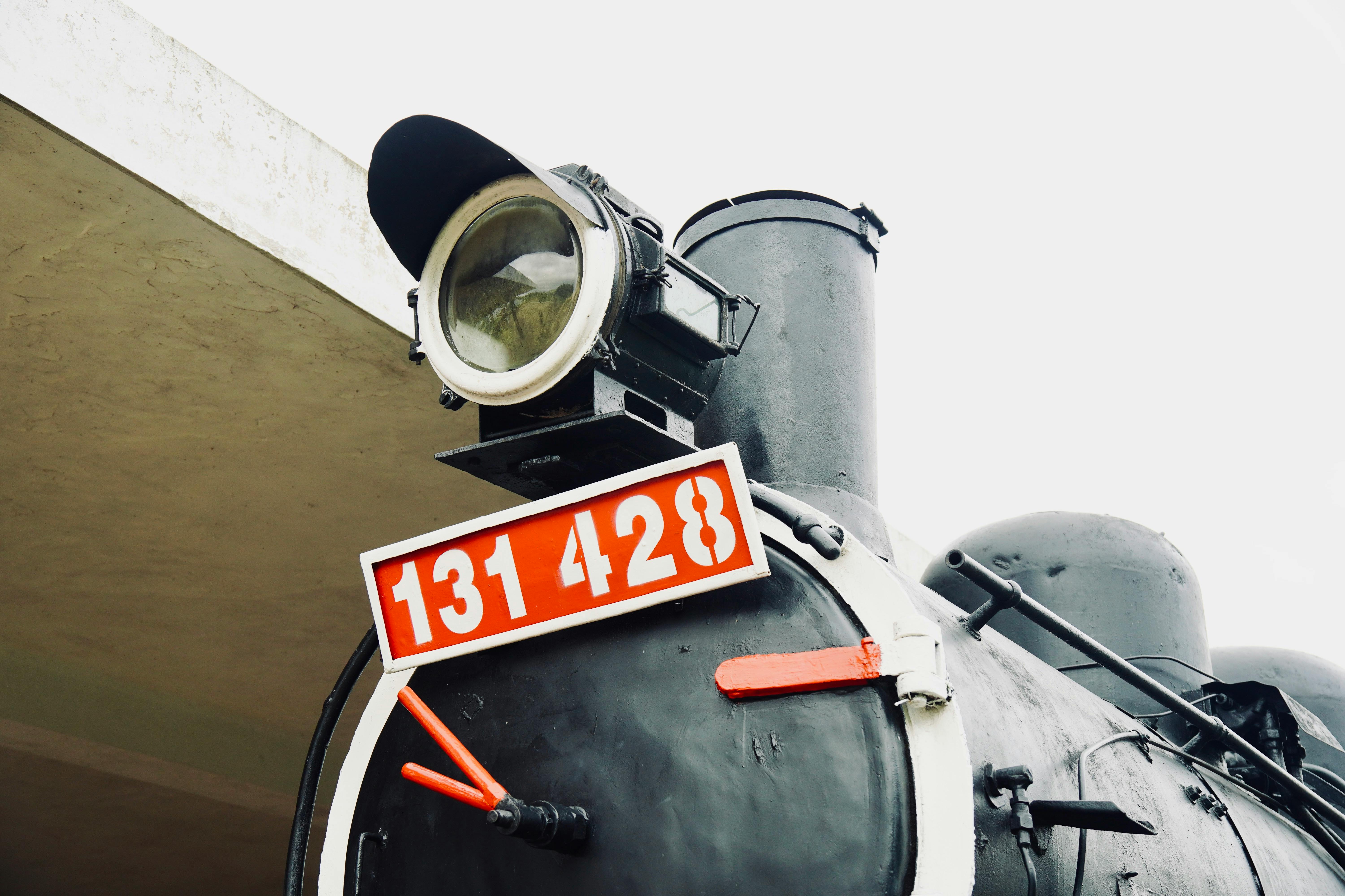 Close-up shot of an old steam locomotive's front with a visible identification plate.