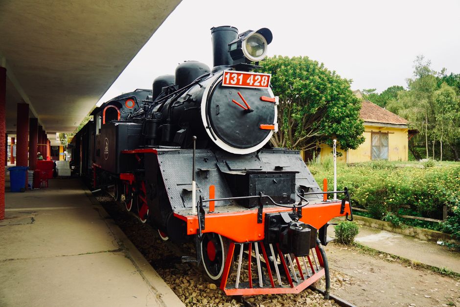 Fotomural Locomotora de vapor histórica en exhibición en una plataforma de estación de tren al aire libre.