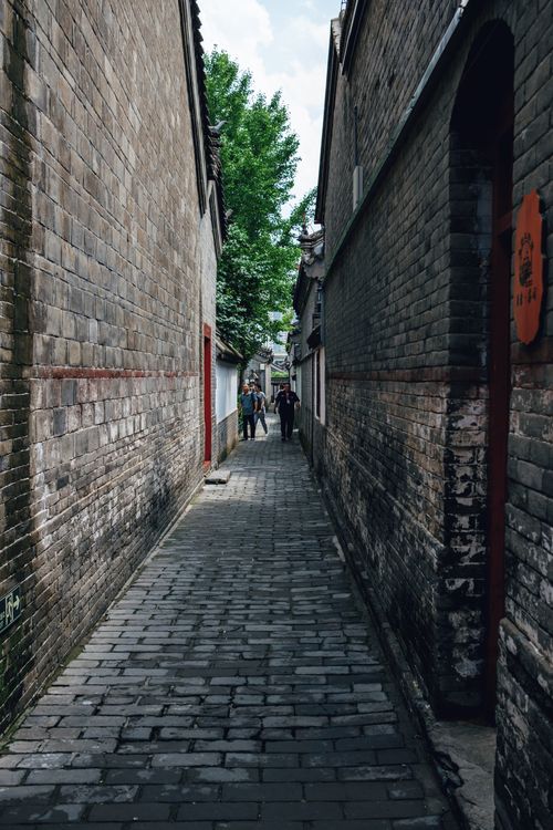 Free Explore a narrow alleyway lined with historic brick walls and traditional architecture in a bustling Asian city. Stock Photo