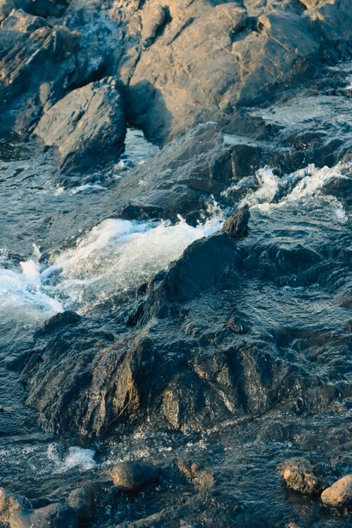 Free Calm river waters cascading gently over rugged rocks in a serene outdoor setting. Stock Photo