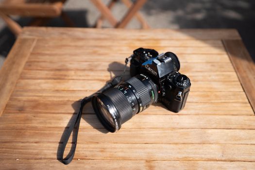 Classic film camera placed on a sunlit wooden table, perfect for vintage photography themes.