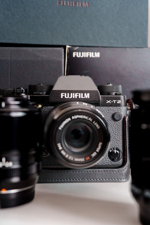 Free Fujifilm X-T2 camera with lens, surrounded by lenses and boxes, showcasing photography gear. Stock Photo
