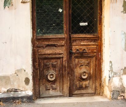 Aged wooden door with intricate carvings in a rustic urban environment, showcasing historical architecture.