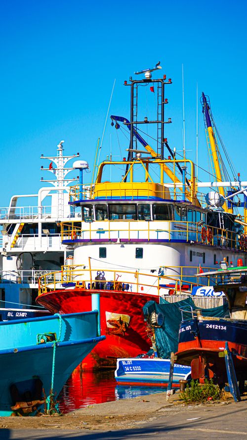 Free Vibrant fishing boats docked at a bustling harbor under a clear sky. Stock Photo