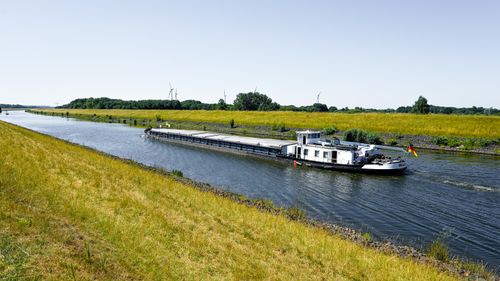 Free A serene view of a canal in Germany with a freight barge and lush greenery, ideal for travel or industrial themes. Stock Photo