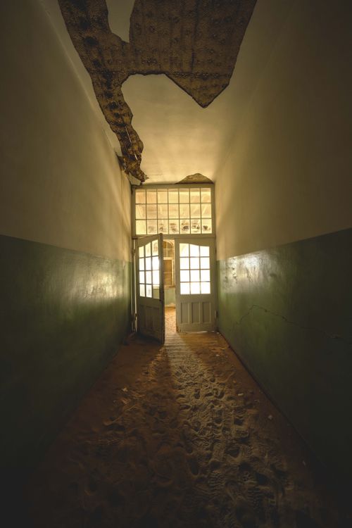 Free Explore the eerie, sand-filled hallway of an abandoned building in Kolmanskop, Namibia. Stock Photo