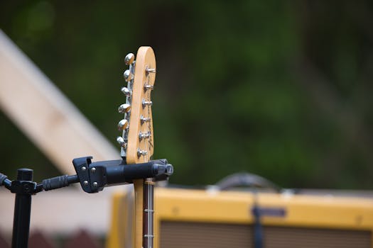 Close-up view of a guitar headstock and amplifier set outdoors, perfect for music-related design.