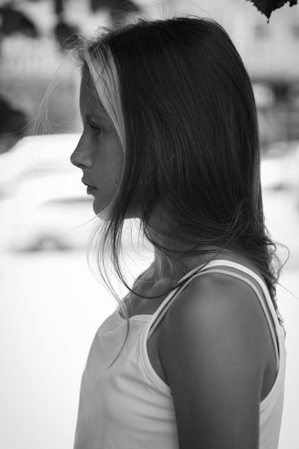 Side profile black and white portrait of a teenage girl outdoors.