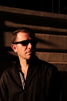 Man in sunglasses with dramatic lighting in an urban environment.