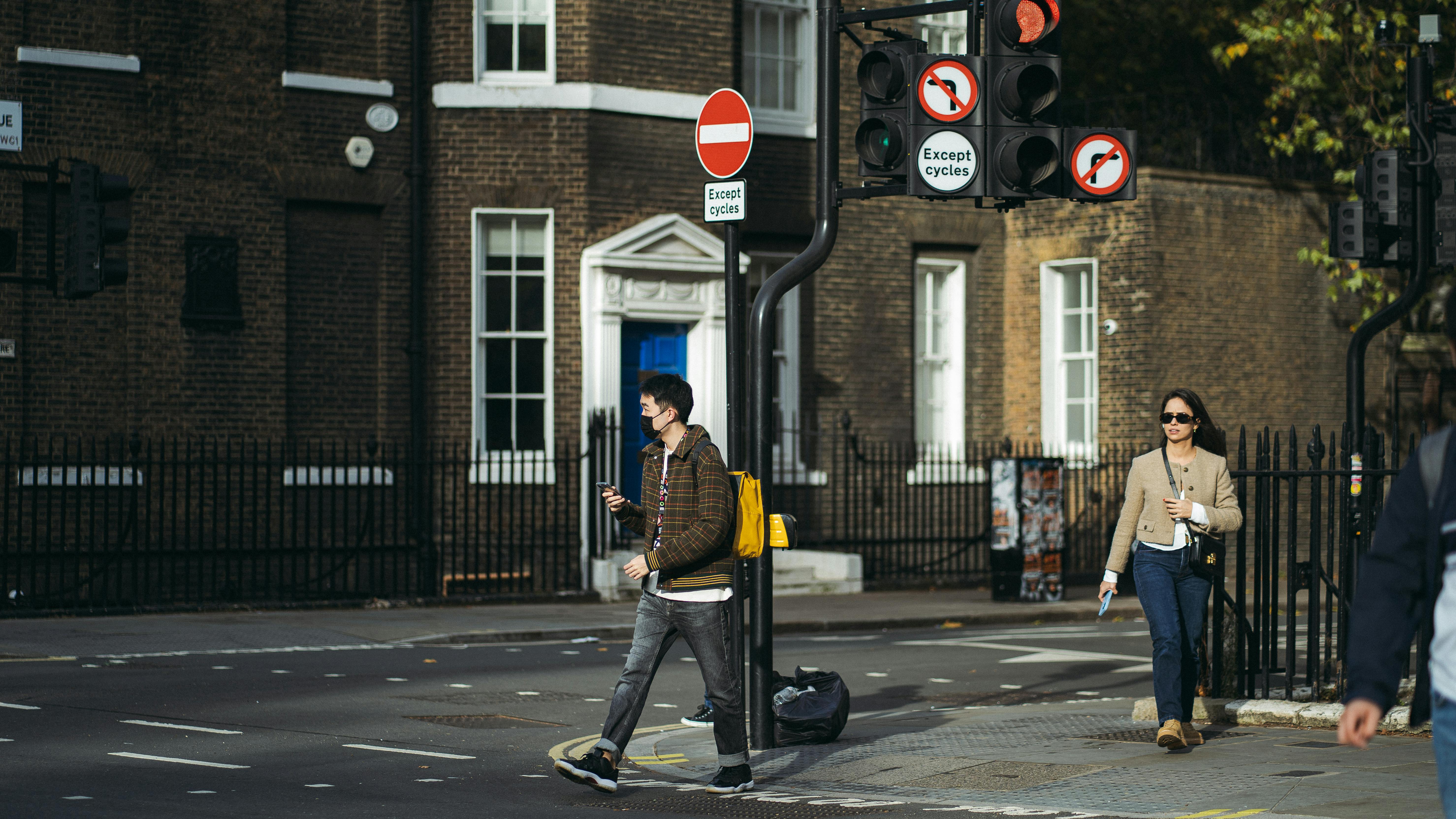 People crossing a street in London on a sunny day, showcasing urban life.