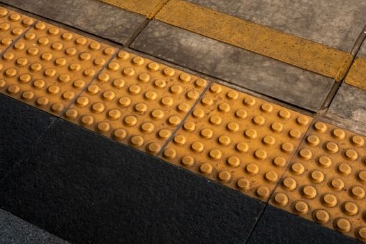 Detailed view of tactile guiding blocks for accessibility at Jakarta train station.