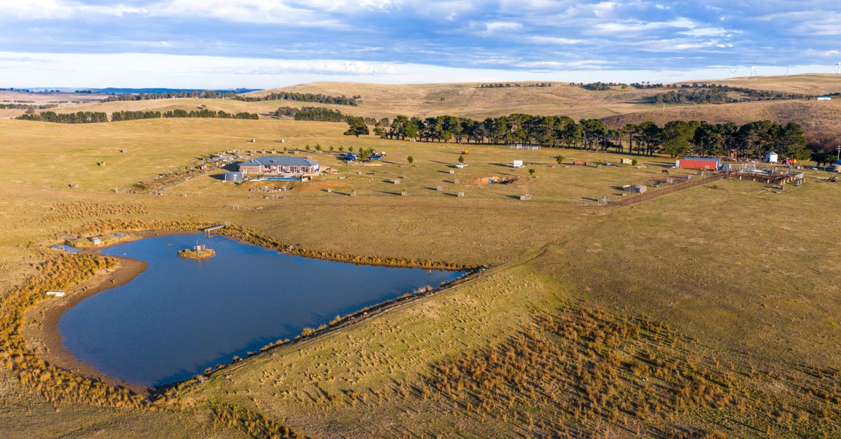 Scenic aerial view of a rural farm landscape with a pond, buildings, and open fields.