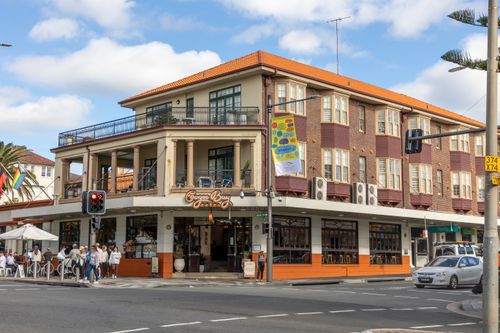 Free Busy corner view of Coogee Bay Hotel in Sydney with people, cars, and vibrant street life. Stock Photo