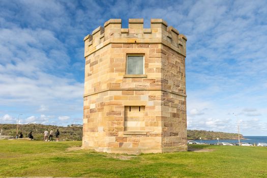 A historic sandstone tower set against a vibrant sky with ocean views.