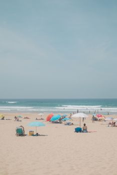 A vibrant beach scene with people relaxing under colorful umbrellas on a sunny day.
