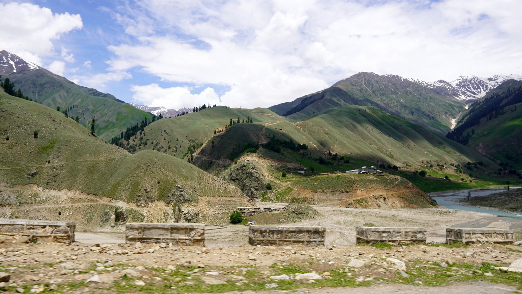 Breathtaking view of Naran Valley's lush hills and river in summer.