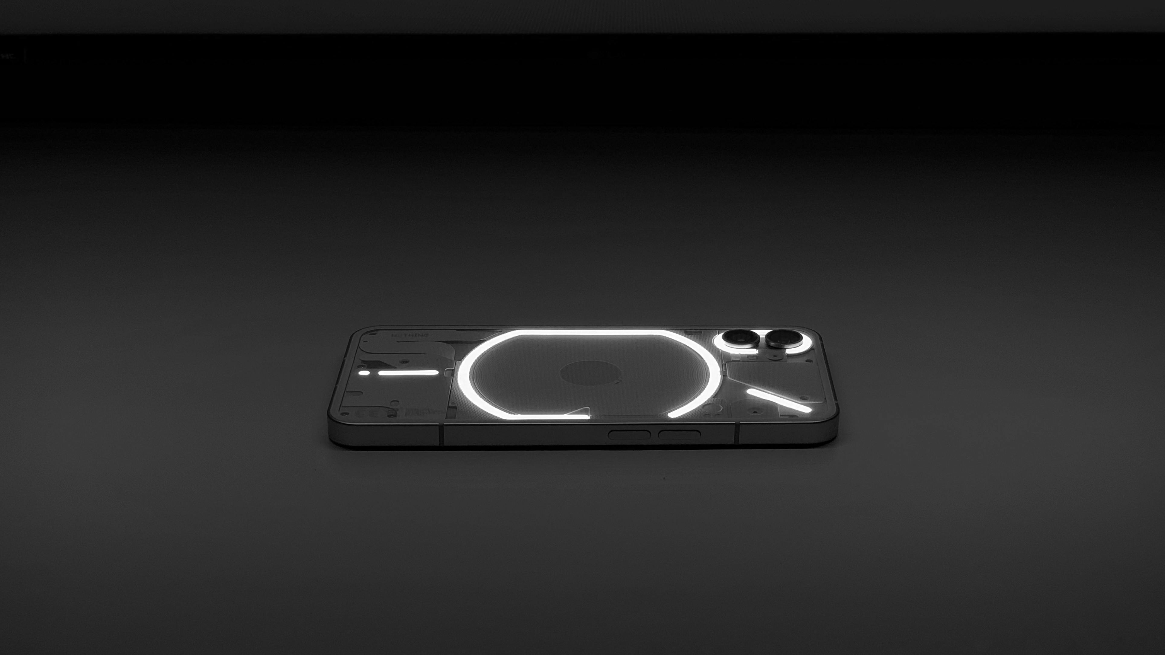 gratis Minimalistische foto van een gloeiende smartphone met een transparante achterkant op een donker oppervlak. Stockfoto