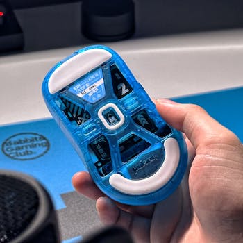 Detailed shot of a transparent blue gaming mouse held in hand, showcasing design and technology.