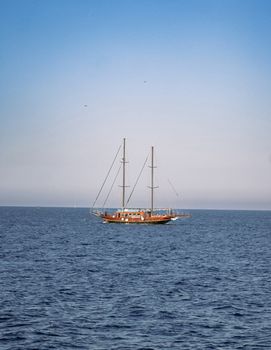 A calm ocean with a sailing boat under a clear blue sky, perfect for travel and adventure themes.