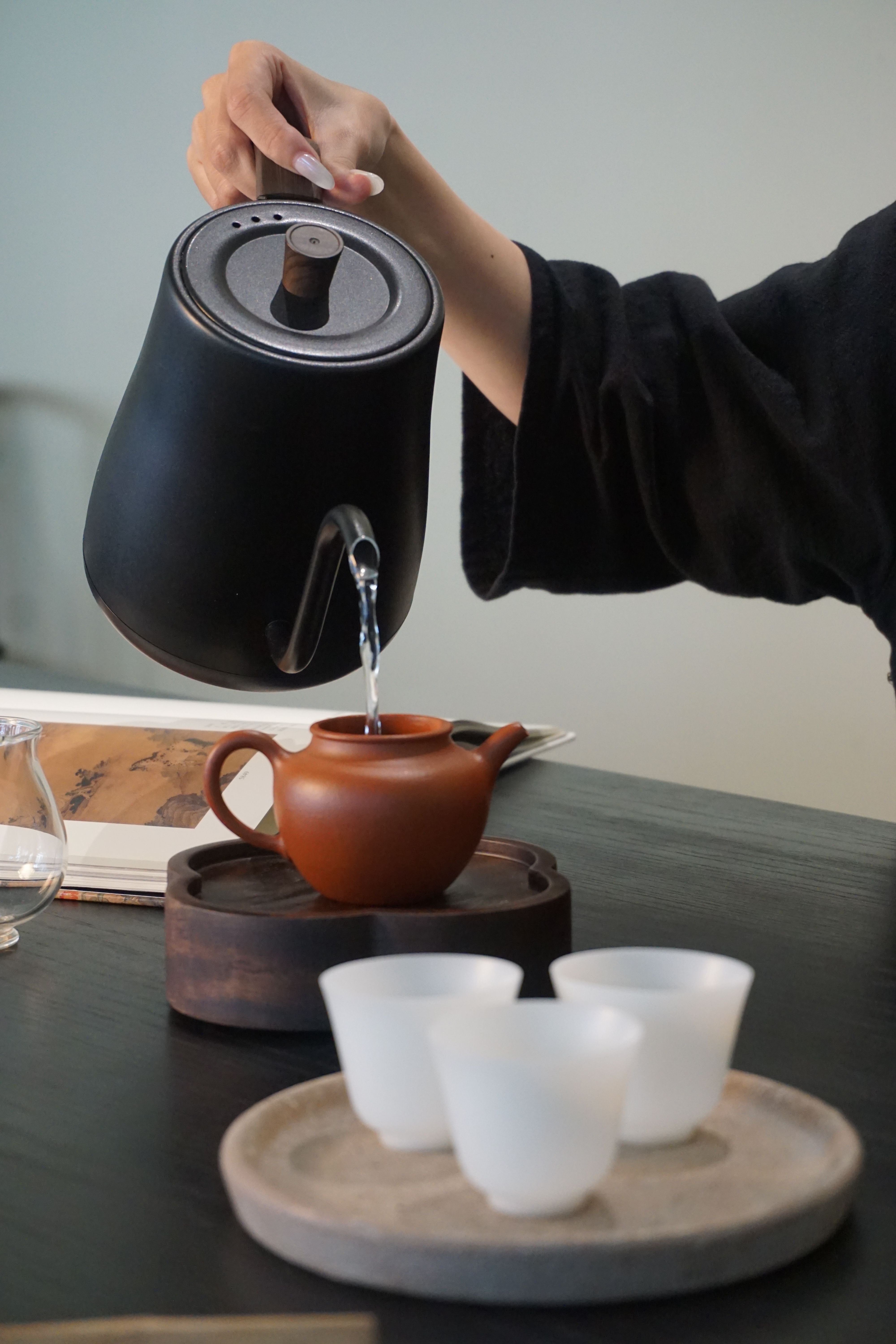 Elegant tea pouring in a serene setting with ceramic teapot and tea cups.