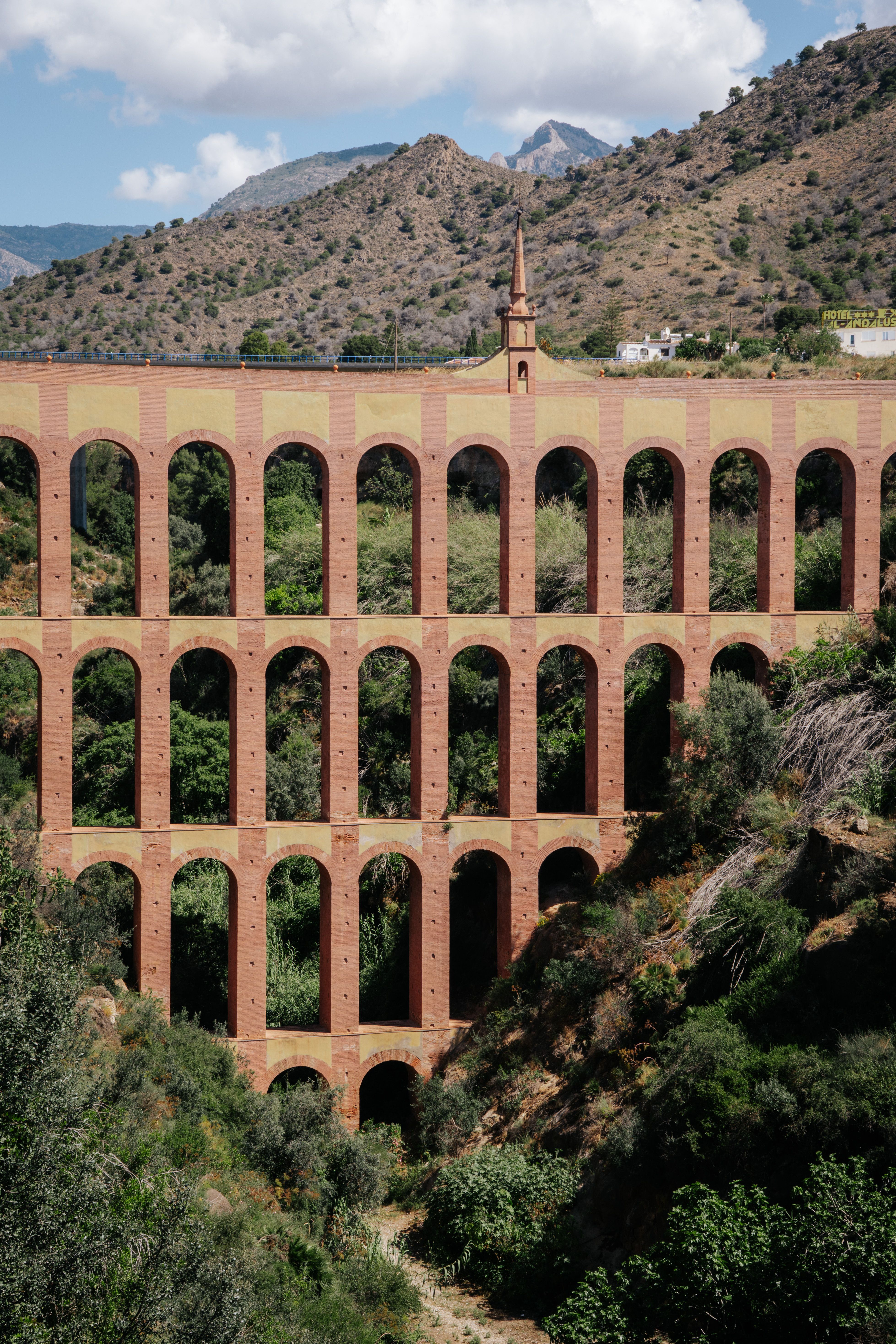 A breathtaking view of the iconic Eagle Aqueduct in Nerja, surrounded by lush greenery and mountains.