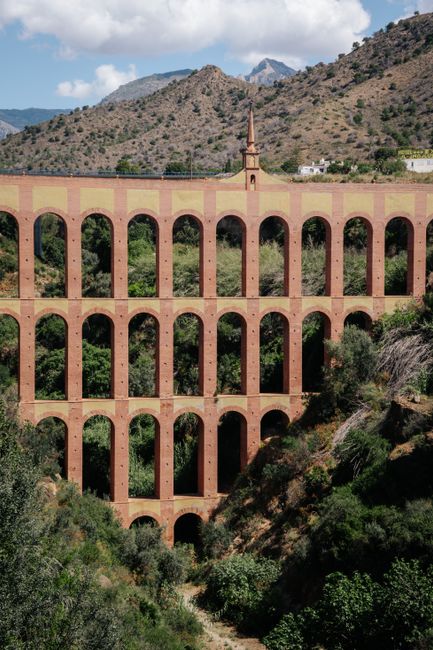 A breathtaking view of the iconic Eagle Aqueduct in Nerja, surrounded by lush greenery and mountains.