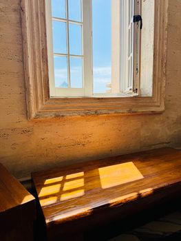 Warm sunlight streaming through an open window casting shadows on a wooden sill.