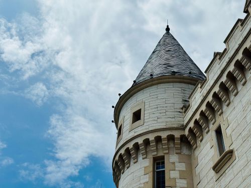 Free Elegant stone castle tower against a bright blue sky with clouds. Stock Photo